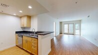 Located on Santa Monica Boulevard in the heart of Santa Monica, CA, this 3-bedroom, 2-bathroom residence offers a well-designed single-floor layout that balances comfort and functionality. The open-concept kitchen and living area serves as the heart of the home, featuring warm hardwood flooring, recessed lighting, and a seamless flow toward French doors that open onto a private balcony, flooding the space with natural light. The kitchen is equipped with light maple cabinetry, dark granite countertops, stainless steel appliances including a refrigerator, range, and dishwasher, and a peninsula with a double sink that connects to the living area. A dedicated in-unit laundry alcove with a stacked washer and dryer adds everyday convenience. The three bedrooms are carpeted and bright, each featuring windows that bring in natural light. The primary bedroom includes access to a closet, while a hallway connects the remaining rooms. The two bathrooms are finished with light maple vanities, dark granite countertops, large mirrors, and tile flooring. One bathroom features a soaking tub with classic white subway tile surround and brushed gold fixtures. A hallway with additional closet storage completes the layout, offering practical organization throughout this well-appointed Santa Monica residence.