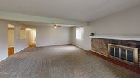 This single-floor residence offers a well-organized layout with a variety of functional and comfortable living spaces throughout. The living room serves as a central highlight, featuring a full-width brick fireplace with a brass-framed glass door and a raised hearth, complemented by an exposed ceiling beam, textured ceiling, and plush carpeting. A vertical-blind window allows natural light to fill the room, enhancing its warm, inviting atmosphere.

The kitchen is thoughtfully appointed with white raised-panel cabinetry, dark laminate countertops, a double stainless steel sink, and wood-look flooring. White appliances, including a range and dishwasher, complete the functional cooking space.

The bedrooms are carpeted and feature neutral-toned walls, ceiling fans with light fixtures, and vertical-blind windows that provide views of surrounding greenery. One bedroom includes a sliding-door closet and direct access to a bathroom. The bathrooms include a tiled shower-and-tub combination with a curtain rod, hardwood-style flooring, and granite-topped vanities.

A covered balcony extends the living space outdoors, featuring wood plank decking and open views of a landscaped green area with mature trees, walking paths, and a picnic area—providing a peaceful outdoor retreat.