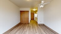 Located at 222 SW Pine St in the heart of Portland, Oregon, this efficiently designed studio unit offers a well-organized single-floor layout that maximizes every square foot. Light-toned luxury vinyl plank flooring runs throughout the entire space, providing a clean, cohesive aesthetic.

The main living area is bright and open, featuring a ceiling fan with integrated lighting and a large, wood-framed window that frames views of mature street trees below, allowing natural light to fill the room. A sliding wood-paneled closet offers convenient built-in storage.

The kitchen runs along one wall in a galley-style configuration, equipped with white cabinetry featuring wood-trimmed accents, a white refrigerator, electric range, and a single-basin sink with under-cabinet storage. Overhead fluorescent lighting illuminates the workspace efficiently.

The bathroom is accessed through a solid wood door and includes a full bathtub with grab bar, a wall-mounted medicine cabinet, a vanity with sink, and durable flooring consistent with the rest of the unit. A wall-mounted heater/ventilation unit provides climate control in the space.

Overall, the unit presents a clean, functional design suited for efficient urban living in downtown Portland.