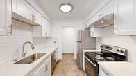 This single-floor residence offers three bedrooms, one bathroom, and a thoughtfully arranged layout that maximizes every square foot. The standout feature is the galley-style kitchen, which is bright and modern with crisp white shaker cabinetry, subway tile backsplash, quartz countertops, and stainless steel appliances including a refrigerator, range, and dishwasher. Light wood-look flooring and a ceiling fan add warmth and functionality to the kitchen space, which also benefits from natural light through a window at the far end.

The three bedrooms are finished with neutral carpet and clean white walls, creating a calm and versatile atmosphere. Each room includes a sliding-door closet with built-in shelving and hanging rods, providing practical storage. The primary bedroom is a comfortable size and features a window with a view of surrounding greenery. The additional bedrooms are well-proportioned, each with a window that brings in natural light.

The bathroom is finished with warm beige large-format wall tiles in the tub-shower surround, wood-look flooring, and a white vanity with a clean countertop. A hallway connects the rooms, contributing to a logical and efficient floor plan. Overall, the space presents a clean, modern, and functional living environment.