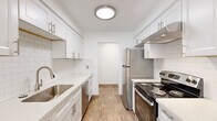 This single-floor residence offers three bedrooms, one bathroom, and a thoughtfully arranged layout that maximizes every square foot. The standout feature is the galley-style kitchen, which is bright and modern with crisp white shaker cabinetry, subway tile backsplash, quartz countertops, and stainless steel appliances including a refrigerator, range, and dishwasher. Light wood-look flooring and a ceiling fan add warmth and functionality to the kitchen space, which also benefits from natural light through a window at the far end.

The three bedrooms are finished with neutral carpet and clean white walls, creating a calm and versatile atmosphere. Each room includes a sliding-door closet with built-in shelving and hanging rods, providing practical storage. The primary bedroom is a comfortable size and features a window with a view of surrounding greenery. The additional bedrooms are well-proportioned, each with a window that brings in natural light.

The bathroom is finished with warm beige large-format wall tiles in the tub-shower surround, wood-look flooring, and a white vanity with a clean countertop. A hallway connects the rooms, contributing to a logical and efficient floor plan. Overall, the space presents a clean, modern, and functional living environment.
