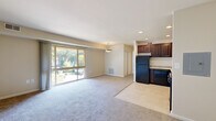 This single-floor unit in Columbia, Maryland offers a practical and well-organized layout designed to maximize functionality. The open-concept living and dining area is finished with neutral-toned carpeting and recessed lighting overhead, creating a bright and welcoming atmosphere. A large sliding glass door draws in abundant natural light while providing views of the surrounding greenery, enhancing the sense of openness throughout the main living space.

The kitchen flows directly from the living area and is appointed with rich, dark-stained wood cabinetry offering ample storage. Light granite-style countertops provide a clean contrast against the cabinetry, while the suite of black appliances—including a gas range, over-the-range microwave, refrigerator, and dishwasher—delivers a cohesive, functional workspace. Tile flooring in the kitchen cleanly delineates the space from the carpeted living area.

The bedroom is a generously sized, quiet retreat finished with soft carpeting and neutral walls. A window allows natural light to enter while maintaining privacy. The overall color palette throughout the unit is soft and neutral, lending a calm, move-in-ready ambiance well-suited to a variety of interior styles.