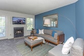 Located at 3145 Lohr Rd in Ann Arbor, Michigan, this multi-floor residence is spread across three levels and offers a well-appointed interior with a blend of modern finishes and bold design choices. The living room serves as a central gathering space, featuring rich teal accent walls, plush carpeting, a fireplace flanked by windows that invite natural light, and direct access to a private balcony. A large wall mirror amplifies the sense of space, while the open layout flows naturally into an adjacent dining area, which benefits from its own window and room for a full dining set.

The kitchen is distinctly modern, outfitted with dark cabinetry, white countertops, stainless steel appliances including a gas range and refrigerator, wood-look flooring, and track lighting. A sliding glass door at the kitchen's far end provides additional outdoor access and natural light.

The bedroom, situated on an upper floor, makes a strong visual statement with a vaulted ceiling and a bold red accent wall. Multiple windows fill the room with natural light, and the carpeted flooring adds warmth. Two bathrooms serve the home—one featuring a floating dark vanity with a vessel sink, and another with wood-look flooring, a tub-shower combination, and a sleek floating vanity. Together, the floors deliver a cohesive, contemporary aesthetic throughout.