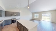 Located at 1700 64th Avenue in Kenosha, WI, this well-designed single-story home offers 3 bedrooms, 2 bathrooms, and a thoughtfully planned layout. The heart of the home is an open-concept living, dining, and kitchen area crowned by soaring vaulted ceilings. The kitchen is a standout, featuring sleek gray shaker cabinets, a white subway tile backsplash, light quartz countertops, a large center island with pendant lighting, and stainless steel appliances. The living room is bright and airy, with hardwood-style flooring, large windows, and a sliding glass door leading to the patio. Bedrooms are carpeted and filled with natural light; the primary suite includes a spacious walk-in closet with built-in shelving and a private en-suite bathroom with a glass-enclosed shower, white vanity, and wood-look flooring. Additional highlights include five closets for ample storage, a dedicated laundry room, a utility room, and an attached garage with interior access. The home's neutral palette and clean finishes create a fresh, move-in-ready ambiance throughout.