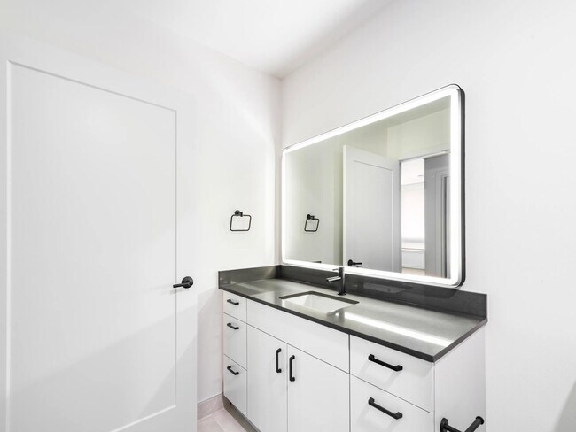 Bathroom vanity with a clean-lined sink, integrated lighting, and streamlined cabinetry creating a bright, functional space for daily routines. - Modera Bridle Trails