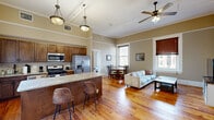 Located in the heart of Macon, GA, this one-bedroom, one-bathroom residence at 610 Mulberry St blends historic charm with modern conveniences. The open-concept main living area showcases warm hardwood floors throughout, soaring ceilings with crown molding, and an abundance of natural light streaming through large, wood-shuttered windows. The kitchen is well-appointed with rich wood cabinetry, granite countertops, stainless steel appliances including a gas range, dishwasher, and French door refrigerator, and a substantial island with bar seating — ideal for both cooking and casual dining. A dedicated dining area accommodates a classic round table and chairs, positioned beside a large window with views of the surrounding Macon streetscape. The spacious bedroom features notably high ceilings, dual windows offering urban views, a dedicated closet, and direct access to the bathroom. The bathroom is finished with tile flooring, a granite-topped vanity with wood cabinetry, a glass-enclosed shower, and warm vanity lighting. A ceiling fan in the living area and pendant lighting over the kitchen island add both function and style, creating a cohesive and comfortable living environment throughout.