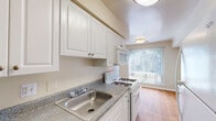 This single-floor residence offers a clean, functional layout designed for comfortable everyday living. The open living and dining area is generously proportioned, featuring warm neutral carpeting and large vertical-blind-covered windows that invite an abundance of natural light throughout the day. The space flows seamlessly, creating a welcoming and airy atmosphere.

The galley-style kitchen is well-appointed with ample white cabinetry, granite-look countertops, a stainless steel double sink, and white appliances including a gas range, over-the-range microwave, and refrigerator. Wood-look flooring adds warmth to the kitchen, which also benefits from a window bringing in additional natural light.

The bedrooms are comfortably sized, each featuring plush carpeting and generous closet space. One bedroom is equipped with a ceiling fan for added comfort, while another includes a dedicated closet with built-in rod and shelving. The rooms are bright and neutral, providing a versatile canvas for personalization.

The bathroom is clean and straightforward, featuring a full soaking tub and shower combination with chrome fixtures, set against crisp white surroundings and wood-look flooring. Throughout the residence, neutral tones and practical finishes create a cohesive, move-in-ready environment.