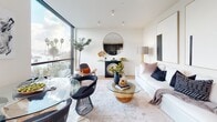 Located in the Palms neighborhood of Los Angeles, unit 526 at 3675 Keystone Ave presents a thoughtfully designed single-floor residence with a clean, contemporary aesthetic. The open-concept living and dining area serves as the heart of the space, anchored by expansive floor-to-ceiling windows that frame views of surrounding palm trees and the Los Angeles skyline, flooding the interior with abundant natural light. A glass-top dining table and modern furnishings complement the bright, white walls and light wood flooring found throughout.

The kitchen is outfitted with sleek, dark concrete-finish cabinetry that extends to the ceiling, stainless steel appliances including a gas range and refrigerator, and a continuous countertop workspace. A horizontal window above the sink provides additional natural light and city views.

The bedroom features a full wall of built-in warm wood-paneled closets with minimalist hardware, creating a serene and organized retreat. A large window offers open views and ample daylight. The bathroom is finished with terrazzo-style flooring and wall tiles, a wall-mounted sink, a large black-framed mirror, and a combined shower and tub enclosed in black-framed glass — delivering a polished, hotel-inspired feel throughout.