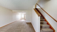 Located at 5591 Rustling Way in Galloway, Ohio, this two-story home offers a practical and well-organized layout spread across two floors. The main level features a carpeted living room with a front entry door and adjacent staircase with a warm wood handrail. The combined kitchen and dining area is equipped with rich cherry-toned cabinetry, granite-look countertops, wood-look flooring, and white appliances including a gas range, dishwasher, and refrigerator. A door off the kitchen provides convenient access to the patio. A full bathroom on this level features a tub/shower combo. The upper floor hosts two bedrooms, each finished with neutral carpet and windows that bring in natural light. The generously sized primary bedroom offers comfortable proportions, while the second bedroom provides similar finishes and an exterior view. A second full bathroom with wood-look flooring and a vanity with warm-toned cabinetry serves the upper level. Additional highlights include four closets for storage, a dedicated laundry area, a utility room, and a hallway connecting the upper-level spaces. Textured ceilings and warm wood trim are consistent throughout, giving the home a cohesive and approachable aesthetic.