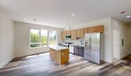 Located at 448 S Orange Ave in Newark, NJ, this well-appointed one-bedroom, one-bathroom unit offers a thoughtfully designed layout with contemporary finishes throughout. The open-concept kitchen is a standout feature, showcasing warm wood cabinetry, dark lower cabinets, a classic subway tile backsplash, and a striking quartz-topped island with subtle veining. A full suite of stainless steel appliances — including a gas range, built-in microwave, dishwasher, and French door refrigerator — makes the kitchen both functional and visually polished. A large picture window floods the space with natural light and offers views of the surrounding greenery. Light-toned luxury vinyl plank flooring runs throughout the unit, lending a clean, modern aesthetic to every room. The spacious bedroom features its own window with outdoor views, recessed lighting, and neutral walls that create a calm, versatile atmosphere. The living area provides generous open space with recessed lighting and a crisp white palette. The bathroom is elegantly finished with large-format marble-style tile in the tub surround, a floating white vanity with matte black fixtures, and a sleek framed mirror, all set against bright white walls and light tile flooring.