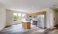 Located at 448 S Orange Ave in Newark, NJ, this well-appointed one-bedroom, one-bathroom unit offers a thoughtfully designed layout with contemporary finishes throughout. The open-concept kitchen is a standout feature, showcasing warm wood cabinetry, dark lower cabinets, a classic subway tile backsplash, and a striking quartz-topped island with subtle veining. A full suite of stainless steel appliances — including a gas range, built-in microwave, dishwasher, and French door refrigerator — makes the kitchen both functional and visually polished. A large picture window floods the space with natural light and offers views of the surrounding greenery. Light-toned luxury vinyl plank flooring runs throughout the unit, lending a clean, modern aesthetic to every room. The spacious bedroom features its own window with outdoor views, recessed lighting, and neutral walls that create a calm, versatile atmosphere. The living area provides generous open space with recessed lighting and a crisp white palette. The bathroom is elegantly finished with large-format marble-style tile in the tub surround, a floating white vanity with matte black fixtures, and a sleek framed mirror, all set against bright white walls and light tile flooring.
