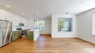 Located at 3939 State Line Rd in Kansas City, MO, this well-appointed 2-bedroom, 2-bathroom residence offers a thoughtfully designed single-level layout. The open-concept living, dining, and kitchen area forms the heart of the home, bathed in natural light from multiple windows overlooking mature trees. The kitchen stands out with sage green lower cabinetry, crisp white upper cabinets, white quartz countertops, stainless steel appliances, a central island with a stainless sink, and sleek pendant lighting overhead. Wood-look flooring flows throughout the main living areas, adding warmth and continuity. Both bedrooms are carpeted and generously sized, each offering walk-in closet space with wire shelving systems. The primary bedroom features large windows that bring in abundant natural light. The bathrooms are finished with white subway tile tub surrounds, white vanities with quartz counters, and matte black hardware accents. Additional conveniences include a laundry area, pantry, utility room, multiple closets, and a private balcony. The entrance and hallway connect the spaces efficiently, completing a clean, modern layout designed for comfortable everyday living.