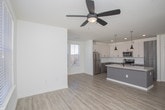 Located at 6271 Riverview Rd SE in Mableton, Georgia, this single-floor residence offers a thoughtfully designed layout with contemporary finishes throughout. The open-concept kitchen serves as the heart of the home, showcasing a large granite-topped center island with an undermount sink and matte black faucet, complemented by two stylish pendant lights overhead. White upper cabinetry pairs with two-tone gray lower cabinets, while a classic subway tile backsplash adds a clean, modern touch. Stainless steel appliances, including a refrigerator, range, and microwave, complete the kitchen's functional appeal. Light hardwood-style flooring flows through the main living areas, seamlessly connecting the kitchen to a generously sized open living space bathed in natural light. The bedrooms feature plush carpeting, ceiling fans, and multiple windows with blinds that invite abundant natural light. One bedroom includes a walk-in closet with built-in shelving, providing ample storage. The two bathrooms are finished with wood-look tile flooring, undermount sinks set in vanities with light countertops, large mirrors, and subway-tiled tub/shower combinations. The overall aesthetic is clean, bright, and move-in ready, reflecting a modern sensibility throughout every room.