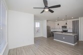 Located at 6271 Riverview Rd SE in Mableton, Georgia, this single-floor residence offers a thoughtfully designed layout with contemporary finishes throughout. The open-concept kitchen serves as the heart of the home, showcasing a large granite-topped center island with an undermount sink and matte black faucet, complemented by two stylish pendant lights overhead. White upper cabinetry pairs with two-tone gray lower cabinets, while a classic subway tile backsplash adds a clean, modern touch. Stainless steel appliances, including a refrigerator, range, and microwave, complete the kitchen's functional appeal. Light hardwood-style flooring flows through the main living areas, seamlessly connecting the kitchen to a generously sized open living space bathed in natural light. The bedrooms feature plush carpeting, ceiling fans, and multiple windows with blinds that invite abundant natural light. One bedroom includes a walk-in closet with built-in shelving, providing ample storage. The two bathrooms are finished with wood-look tile flooring, undermount sinks set in vanities with light countertops, large mirrors, and subway-tiled tub/shower combinations. The overall aesthetic is clean, bright, and move-in ready, reflecting a modern sensibility throughout every room.