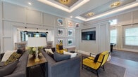 This single-floor clubhouse facility is thoughtfully designed to serve as a refined community gathering space, offering a variety of distinct areas united by a cohesive upscale aesthetic. The grand entrance immediately impresses with soaring ceilings, oversized black ironwork French doors, arched transom windows, and a bold black-and-white checkered tile floor that sets an elegant tone throughout. Large globe pendant lights illuminate the expansive lobby, which features multiple seating arrangements and opens into the broader common areas.

The lounge area is appointed with coffered tray ceilings accented by subtle ambient lighting, wainscoting wall panels, and a curated gallery wall of framed artwork. Plush charcoal sofas are paired with bold mustard-yellow accent chairs, creating a striking contrast against the neutral palette. A wall-mounted flat-screen television is seamlessly integrated into the paneling.

Adjacent, a dining and social room features deep navy walls, high ceilings, and a built-in bar with bar-stool seating, pendant lighting, and a wall-mounted display screen. A dedicated conference room offers a textured accent wall, a flat-screen display, and a central work table ideal for meetings.

The catering kitchen is well-appointed with navy cabinetry, white quartz countertops, wood-look tile flooring, and pendant lighting, providing practical functionality alongside polished design.