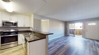 Located at 2450 Hilton Head Pl in El Cajon, California, this single-floor residence offers a clean, modern layout designed for comfortable everyday living. The entryway welcomes you through a white paneled front door with a transom window, opening into a bright, open-concept living and dining area finished with smooth wood-look laminate flooring and neutral gray walls throughout.

The kitchen is thoughtfully designed with white shaker-style cabinetry extending to the ceiling, dark countertops, and a full suite of stainless steel appliances including a refrigerator, range, and microwave. A peninsula with an undermount sink and extended counter space connects the kitchen to the living area, making it ideal for both cooking and entertaining. A sliding glass door off the living space provides access to an outdoor area and brings in natural light.

The bedrooms feature plush carpeting and large windows fitted with vertical blinds, allowing for adjustable natural light and outdoor views. The bathroom includes a full tub and shower combination with chrome fixtures. A second bathroom area offers a wide vanity with dark countertops, a vessel sink, a large mirror, and access to a walk-in closet. In-unit laundry is conveniently tucked behind a door adjacent to the kitchen.