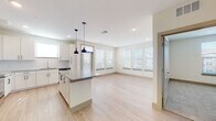 This single-floor residence showcases a thoughtfully designed open-concept layout that seamlessly connects the kitchen and living areas. The kitchen serves as the centerpiece of the space, featuring crisp white shaker cabinetry extending to the ceiling, a granite-topped center island illuminated by stylish pendant lights, and a full suite of stainless steel appliances including a French door refrigerator, range, microwave, and dishwasher. A classic subway tile backsplash and light hardwood-style flooring complete the kitchen's clean, contemporary aesthetic.

The open living area extends naturally from the kitchen, bathed in natural light from multiple windows dressed with horizontal blinds. The seamless flow between these spaces creates an airy, connected atmosphere ideal for everyday living.

The bedrooms offer a comfortable retreat, finished with plush wall-to-wall carpeting and windows that bring in natural light. Each room provides a calm, neutral backdrop adaptable to various needs.

The bathrooms are well-appointed with granite countertops, dual undermount sinks, large mirrors, white cabinetry, and a soaking tub with shower combination. Light hardwood-style flooring ties these spaces together with the rest of the home, maintaining a consistent and polished design throughout.