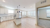 This single-floor residence showcases a thoughtfully designed open-concept layout that seamlessly connects the kitchen and living areas. The kitchen serves as the centerpiece of the space, featuring crisp white shaker cabinetry extending to the ceiling, a granite-topped center island illuminated by stylish pendant lights, and a full suite of stainless steel appliances including a French door refrigerator, range, microwave, and dishwasher. A classic subway tile backsplash and light hardwood-style flooring complete the kitchen's clean, contemporary aesthetic.

The open living area extends naturally from the kitchen, bathed in natural light from multiple windows dressed with horizontal blinds. The seamless flow between these spaces creates an airy, connected atmosphere ideal for everyday living.

The bedrooms offer a comfortable retreat, finished with plush wall-to-wall carpeting and windows that bring in natural light. Each room provides a calm, neutral backdrop adaptable to various needs.

The bathrooms are well-appointed with granite countertops, dual undermount sinks, large mirrors, white cabinetry, and a soaking tub with shower combination. Light hardwood-style flooring ties these spaces together with the rest of the home, maintaining a consistent and polished design throughout.