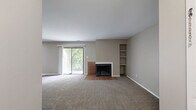Located at 5340 Acorn Ln in Indianapolis, IN, this two-bedroom, one-bathroom residence offers a well-organized single-floor layout with a comfortable and functional flow. The spacious living room serves as the heart of the home, anchored by a classic wood-burning fireplace with a brick tile hearth and flanked by built-in shelving — ideal for display or storage. A sliding glass door fills the room with natural light and provides direct access to a private balcony overlooking lush greenery. Neutral-toned carpet and warm beige walls carry throughout the living spaces, creating a cohesive and inviting atmosphere. The galley-style kitchen features dark cabinetry, light stone-look countertops, wood-look tile flooring, and includes a refrigerator and range. An adjacent dining area provides a dedicated space for meals. The primary bedroom is generously sized, complete with a large bi-fold closet and an additional closet for ample storage. The second bedroom benefits from a bright window with wooded views and plush carpeting. The full bathroom includes a white vanity with under-cabinet storage, a mirrored medicine cabinet with lighted vanity bar, and tile flooring. A utility room, entrance hallway, and five closets in total round out the practical features of this well-appointed home.