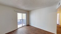 This single-floor unit offers a practical and well-organized layout across several distinct spaces. The living area is finished with dark wood-look flooring and features a textured ceiling, neutral walls, and a sliding glass door that opens to a private balcony, allowing natural light to fill the room and providing outdoor views of surrounding greenery.

The galley-style kitchen is efficiently designed with dark wood cabinetry lining both walls, offering generous storage above and below the counters. White appliances include an electric range, dishwasher, and refrigerator, complemented by a double-basin sink and light countertops. Wood-look flooring continues throughout this space.

The unit includes two bedrooms, both featuring plush carpeting and neutral walls. One bedroom is equipped with a ceiling fan and light fixture, along with a window fitted with blinds. The other bedroom provides a quiet, carpeted retreat with closet access.

Two bathrooms serve the unit. The primary bathroom includes an extended vanity with a wide mirror, wood-grain cabinetry, and strip lighting above. A half bath offers a single-sink vanity with matching cabinetry, a mirror, and wood-look flooring. Both bathrooms maintain a clean, functional aesthetic consistent with the rest of the unit.