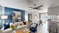 This single-floor residence at 2020 Armstrong Mill Rd in Lexington, Kentucky offers a thoughtfully designed layout comprising a living room, dining area, kitchen, bedroom, bathroom, closet, laundry room, and hallway. The open-concept living and dining area is anchored by wood-look flooring, a ceiling fan with light fixture, and a bold navy accent wall that adds depth and character. Large windows with blinds and patterned drapes invite natural light throughout the space, with sliding glass doors providing outdoor access from the dining area. The kitchen features dark, shaker-style cabinetry, granite countertops, a white subway tile backsplash, a double-basin sink, and stainless steel appliances. The dining space accommodates a round glass-top table and is finished with a modern track light fixture. The carpeted bedroom includes a ceiling fan, a bold navy accent wall, and ample room for a full furniture arrangement. The bathroom offers wood-look tile flooring, a granite-topped vanity with dark cabinetry, and a shower/tub combo. A dedicated in-unit laundry room includes side-by-side washer and dryer units with built-in shelving, completing this efficient and stylish home.