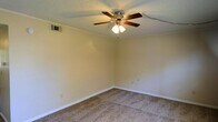 This two-floor property offers a straightforward and functional layout designed for comfortable everyday living. The interior showcases wall-to-wall carpeting in a neutral tone, providing a warm and cohesive feel underfoot. Crown molding runs along the upper perimeter of the walls, adding a subtle architectural detail that lends a classic character to the space. The walls are finished in a soft, neutral hue, creating a clean and versatile backdrop suitable for a variety of décor styles. A ceiling-mounted fan with an integrated light fixture provides both ventilation and ambient lighting, while a textured popcorn ceiling adds dimension overhead. HVAC venting is integrated into the walls, ensuring efficient climate control throughout. White baseboards frame the floors cleanly, complementing the overall light and airy feel of the interior. The two-floor configuration provides a natural separation of living and private spaces, offering both functionality and practicality. Overall, the space presents a well-maintained, move-in-ready environment with classic details and neutral finishes that provide a solid foundation for personalization.