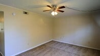 This two-floor property offers a straightforward and functional layout designed for comfortable everyday living. The interior showcases wall-to-wall carpeting in a neutral tone, providing a warm and cohesive feel underfoot. Crown molding runs along the upper perimeter of the walls, adding a subtle architectural detail that lends a classic character to the space. The walls are finished in a soft, neutral hue, creating a clean and versatile backdrop suitable for a variety of décor styles. A ceiling-mounted fan with an integrated light fixture provides both ventilation and ambient lighting, while a textured popcorn ceiling adds dimension overhead. HVAC venting is integrated into the walls, ensuring efficient climate control throughout. White baseboards frame the floors cleanly, complementing the overall light and airy feel of the interior. The two-floor configuration provides a natural separation of living and private spaces, offering both functionality and practicality. Overall, the space presents a well-maintained, move-in-ready environment with classic details and neutral finishes that provide a solid foundation for personalization.