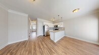 Located at 1637 Marakanda Trail in Sugar Hill, GA, this two-story townhome offers a well-organized layout across two floors. The main level features an open-concept living, dining, and kitchen area finished with warm hardwood-style flooring and crown molding throughout. The kitchen is equipped with white shaker cabinetry, granite countertops, a tile backsplash, stainless steel appliances, and a peninsula island with pendant lighting — ideal for both cooking and casual entertaining. A convenient half bathroom and garage access are also found on this level, along with a patio for outdoor enjoyment.

Upstairs, the layout includes two spacious bedrooms, each benefiting from natural light through sizable windows. The generously sized primary bedroom features its own dedicated bathroom and a walk-in closet with built-in wire shelving. Additional closets throughout provide ample storage. Two full bathrooms serve the upper level, and a dedicated laundry area adds everyday convenience. Hallways are well-proportioned and accented with crown molding, reinforcing the home's clean, consistent aesthetic.

The exterior presents a classic brick-and-siding facade with an attached single-car garage, a private driveway, and manicured landscaping. Set in the Sugar Hill community, the home is surrounded by lush greenery, offering a peaceful suburban setting.