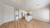 Located at 1637 Marakanda Trail in Sugar Hill, GA, this two-story townhome offers a well-organized layout across two floors. The main level features an open-concept living, dining, and kitchen area finished with warm hardwood-style flooring and crown molding throughout. The kitchen is equipped with white shaker cabinetry, granite countertops, a tile backsplash, stainless steel appliances, and a peninsula island with pendant lighting — ideal for both cooking and casual entertaining. A convenient half bathroom and garage access are also found on this level, along with a patio for outdoor enjoyment.

Upstairs, the layout includes two spacious bedrooms, each benefiting from natural light through sizable windows. The generously sized primary bedroom features its own dedicated bathroom and a walk-in closet with built-in wire shelving. Additional closets throughout provide ample storage. Two full bathrooms serve the upper level, and a dedicated laundry area adds everyday convenience. Hallways are well-proportioned and accented with crown molding, reinforcing the home's clean, consistent aesthetic.

The exterior presents a classic brick-and-siding facade with an attached single-car garage, a private driveway, and manicured landscaping. Set in the Sugar Hill community, the home is surrounded by lush greenery, offering a peaceful suburban setting.