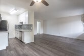 Located at 6300 Lankershim Blvd in North Hollywood, this single-floor unit offers a clean, modern interior with a thoughtfully designed open-concept layout. Warm hardwood-style flooring runs throughout the space, creating a cohesive and inviting atmosphere from room to room.

The kitchen is a functional galley-style design featuring white shaker cabinetry with brushed nickel hardware, light quartz countertops, and a striking mosaic tile backsplash in a dark glass-and-stone pattern. Stainless steel appliances — including a gas range, microwave, refrigerator, and dishwasher — complete the space. A peninsula counter extends into the living area, defining the kitchen zone while maintaining an open flow.

The living area is generously proportioned, bathed in natural light from multiple windows fitted with vertical blinds. A ceiling fan adds comfort, and a wall-mounted HVAC unit provides climate control. The open sightlines from the kitchen through to the living area and beyond give the space a connected, airy feel.

The bedroom is spacious and bright, benefiting from a large sliding glass door that invites natural light. A full bathroom with a tub/shower combination and warm tile surround is conveniently accessible. A separate vanity area with a wide mirror, white cabinetry, and a single-basin sink adds practicality and a polished finish to the private quarters.