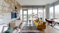Located at 1000 Lake St in Oak Park, Illinois, this thoughtfully designed single-floor residence combines modern architecture with contemporary finishes throughout. The open-concept living area is anchored by expansive floor-to-ceiling windows that flood the space with natural light and offer sweeping views of the surrounding neighborhood skyline, creating an airy, connected ambiance.

The kitchen is a standout feature, appointed with textured wood-grain cabinetry, clean white quartz countertops, a herringbone-patterned tile backsplash, and a full suite of stainless steel appliances including a gas range and French door refrigerator. Open shelving adds both functionality and visual interest.

The bedrooms are generously proportioned, with plush carpeting and large windows — one featuring floor-to-ceiling glass that brings in abundant daylight and urban views. Ample closet space is provided throughout.

The primary bathroom is bright and modern, finished in light neutral tones with a frameless glass walk-in shower, while the secondary bathroom offers a full soaking tub and shower combination with a wood-toned vanity. A dedicated in-unit laundry area houses a stacked washer and dryer for added convenience.

Light hardwood flooring flows through the main living areas, uniting the space with warmth and cohesion.