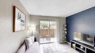 Located at 2800 Mustang Rd in Alvin, TX, this one-bedroom, one-bathroom unit offers a thoughtfully organized single-floor layout that maximizes its compact footprint. Light wood-look flooring runs throughout, complementing a neutral warm-gray color palette that lends a cohesive, modern feel to the entire space.

The living room serves as a welcoming focal point, anchored by a striking navy blue accent wall and a sliding glass door that opens onto a private balcony, drawing in natural light. A pass-through window with built-in shelving connects the living area to the kitchen, enhancing the open feel between spaces.

The galley-style kitchen is efficiently designed, featuring dark cabinetry contrasted by marble-look countertops, a stainless steel sink, and black appliances including a range and refrigerator. Adjacent to the kitchen, the dining area accommodates intimate seating and benefits from natural light via a window overlooking the balcony.

The bedroom is a comfortable, well-proportioned retreat with a ceiling fan, a window offering outdoor views, and dedicated closet storage. The bathroom includes a full tub-shower combination with clean white tile surround. Throughout, the unit presents a functional and polished living environment.