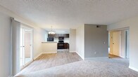 This single-floor unit offers a well-organized layout that balances open communal spaces with private areas. The living room is generously sized, finished with plush carpet and anchored by a tiled fireplace along one wall. A sliding glass door fills the space with natural light and provides access to an outdoor area, creating a bright, welcoming atmosphere. The textured ceiling is consistent throughout the main living areas.

The kitchen is positioned adjacent to the living space and is separated by a half-wall breakfast bar, maintaining an open feel while defining the cooking zone. Dark espresso cabinetry lines the walls and provides ample storage, complemented by light countertops and wood-look vinyl flooring. Black appliances, including a refrigerator, range, and microwave, are included. A window above the counter draws in additional natural light.

The dining area sits just off the kitchen and features a chandelier overhead, adding a decorative touch to the space.

The bedrooms are carpeted and offer a calm, neutral aesthetic. Each includes a window for natural light, and at least one bedroom features a sliding-door closet with built-in shelving. Two bathrooms serve the unit, both finished with wood-look vinyl flooring and tub-shower combinations, with one featuring a vanity with dark cabinetry.
