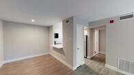 Located on Presidential Boulevard in Philadelphia, PA, this one-bedroom, one-bathroom residence offers a thoughtfully designed layout with modern finishes and functional living spaces. The open living room serves as the heart of the home, highlighted by a sleek black-surround fireplace with a white mantle and a sliding glass door that opens to a private balcony, filling the space with natural light. Durable wood-look flooring runs throughout the main living areas, complementing the neutral, warm-toned walls. The kitchen features dark wood cabinetry, a stainless steel sink, light countertops, and a stainless electric range, with a pass-through counter connecting it to the living area for an open, functional feel. The spacious bedroom is finished with soft carpet, a dedicated closet, and a window that allows natural light to brighten the room. The bathroom is well-appointed with a full soaking tub, a striking striped tile surround in layered grey tones, and clean white shiplap-style wall tiles. A dedicated closet and hallway provide practical storage and circulation. The textured ceilings and consistent neutral palette throughout lend the space a cohesive, move-in-ready character.