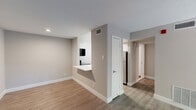 Located on Presidential Boulevard in Philadelphia, PA, this one-bedroom, one-bathroom residence offers a thoughtfully designed layout with modern finishes and functional living spaces. The open living room serves as the heart of the home, highlighted by a sleek black-surround fireplace with a white mantle and a sliding glass door that opens to a private balcony, filling the space with natural light. Durable wood-look flooring runs throughout the main living areas, complementing the neutral, warm-toned walls. The kitchen features dark wood cabinetry, a stainless steel sink, light countertops, and a stainless electric range, with a pass-through counter connecting it to the living area for an open, functional feel. The spacious bedroom is finished with soft carpet, a dedicated closet, and a window that allows natural light to brighten the room. The bathroom is well-appointed with a full soaking tub, a striking striped tile surround in layered grey tones, and clean white shiplap-style wall tiles. A dedicated closet and hallway provide practical storage and circulation. The textured ceilings and consistent neutral palette throughout lend the space a cohesive, move-in-ready character.