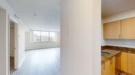 Located at 10301 Grosvenor Pl in Rockville, MD, this one-bedroom, one-bathroom residence offers a thoughtfully designed single-floor layout. The open-concept living and dining area is bright and airy, featuring light hardwood-style flooring and large windows that frame outdoor views and flood the space with natural light. A sliding door provides direct access to a private balcony, extending the living area outdoors.

The kitchen is positioned adjacent to the living area and features a pass-through counter with a granite-topped breakfast bar, warm wood cabinetry, stainless steel appliances including a refrigerator and microwave, and a built-in sink — making it both functional and visually connected to the main living space.

The generously sized bedroom is carpeted for comfort and includes a large window with balcony access, offering ample natural light and outdoor views. The room provides comfortable living space suitable for a full bedroom suite.

The bathroom is clean and well-appointed, featuring granite countertops, a wood-toned vanity with an undermount sink, a large mirror, tile flooring, and a full soaking tub with shower. A hallway connects all areas of the unit efficiently. Throughout, a neutral color palette and consistent finishes create a cohesive and inviting atmosphere.