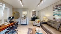 Located at 1025 S Crater Rd in Petersburg, Virginia, this single-floor commercial space offers a well-organized and efficiently utilized layout comprising a living room, dining room, dedicated office, and a full bathroom. Light wood-look flooring runs throughout, creating a clean and cohesive aesthetic across all areas.

The living room serves as a welcoming reception area, featuring track lighting, a leather sofa, and French doors that flood the room with natural light and provide a view of the surrounding greenery. Adjacent to it, the dining room functions as a conference area, centered around a solid wood table with upholstered seating, metal filing cabinets for storage, and cityscape wall art that adds a professional touch. A window brings in additional natural light, enhancing the room's functionality.

The dedicated office is equipped with a large L-shaped desk, ergonomic seating, and a window with outdoor views — ideal for administrative work. A kitchenette is visible from the main area, providing added convenience. The bathroom is clean and straightforward, featuring a single-sink vanity with cabinet storage, a mirror, and wood-look tile flooring. Textured ceilings are present throughout, and neutral wall tones contribute to a professional and inviting atmosphere throughout the space.