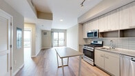 Located at 880 Pacific St in Stamford, Connecticut, this modern one-bedroom, one-bathroom residence offers a well-designed open-concept layout with contemporary finishes throughout. Wide-plank wood-style flooring runs seamlessly across the entire unit, lending warmth and continuity to every room.

The open kitchen and living area form the heart of the home. The kitchen is outfitted with light wood cabinetry extending to the ceiling, a subway tile backsplash, stainless steel appliances including a gas range, microwave, dishwasher, and refrigerator, and a central island that provides additional prep and dining space. Track lighting above enhances both function and ambiance.

The living area opens directly to a private balcony via sliding glass doors, offering elevated views of a nearby marina with boats and waterways — a standout feature of this residence. The bedroom also benefits from floor-to-ceiling windows framing the same striking marina scenery, filling the room with natural light.

The bathroom is clean and modern, featuring white subway tile surrounding a soaking tub and shower combination, wood-style flooring, a sleek vanity, and an illuminated mirror. Additional highlights include three closets for ample storage, an in-unit laundry area, and a well-connected hallway layout that ensures privacy between living and sleeping spaces.