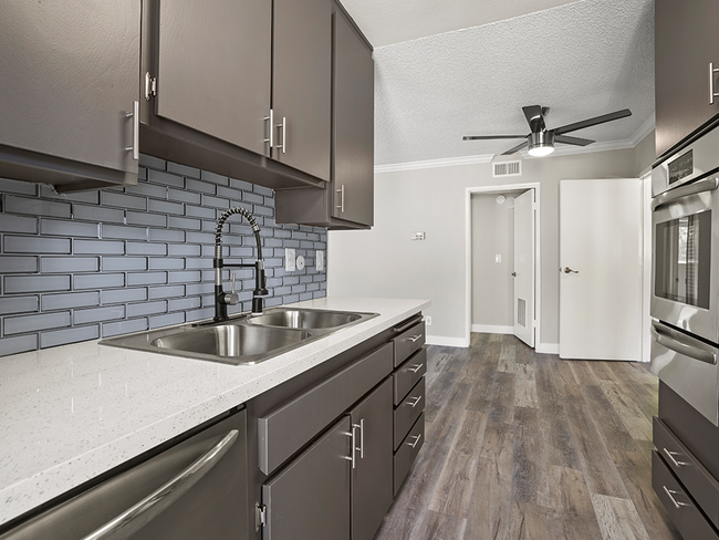 Blue tiled kitchen with stainless steel oven, microwave, and fixtures. - Tilden II Apartments