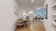 Located at 4520 Charlotte Park Dr in Charlotte, NC, this well-appointed two-bedroom, two-bathroom residence offers a thoughtfully designed single-floor layout with a bright, open-concept living space. Wide-plank wood-style flooring flows throughout the main areas, complementing the clean white walls and recessed lighting that create an airy, modern ambiance.

The kitchen is a standout feature, boasting granite countertops, white shaker cabinetry, a subway tile backsplash, stainless steel appliances, and a large center island with a built-in sink and pendant lighting overhead — ideal for both cooking and entertaining. The dining area sits adjacent, offering a seamless transition into the spacious living room, which is highlighted by soaring ceilings and generous windows that invite abundant natural light.

The primary bedroom features impressively high ceilings, plush carpeting, and direct access to a closet and en-suite bath. The second bedroom is equally comfortable, with large windows framing outdoor greenery. Both bathrooms are finished with granite-topped vanities and wood-style flooring. A dedicated in-unit laundry room adds everyday convenience, completing this functional and stylish Charlotte residence.