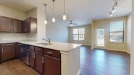 This thoughtfully designed one-bedroom, one-bathroom residence offers a comfortable and functional layout across a single floor. The open-concept kitchen and living area serves as the heart of the home, where rich dark-cabinetry kitchen with granite-style countertops, stainless steel appliances, and a peninsula island with pendant lighting flows seamlessly into the living room. Hardwood-style flooring extends throughout the main living areas, complemented by natural light from multiple windows and ceiling fans that enhance both comfort and airflow.

The kitchen is well-equipped with ample cabinetry, a stainless steel refrigerator, range, and microwave, along with a double-basin sink on the peninsula. The living room is generously proportioned, featuring a ceiling fan and a large window that brings in natural light.

The bedroom offers a cozy carpeted floor, a ceiling fan, and a window with exterior views, providing a quiet and restful retreat. It is accompanied by a spacious walk-in closet outfitted with wire shelving and carpet flooring, offering substantial storage capacity.

The bathroom features a full tub-shower combination with diagonal tile surround and a decorative mosaic accent border, dark cabinetry vanity with a granite-style countertop, and hardwood-style flooring, creating a clean and polished finish throughout.