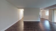 Located at 6114 Edsall Rd in Alexandria, Virginia, this single-floor unit offers a well-organized layout designed for comfortable everyday living. The open living and dining area is defined by rich, dark hardwood-style flooring and neutral-toned walls, creating a clean and versatile backdrop. Natural light filters in through windows, enhancing the sense of openness throughout the space.

The kitchen features warm, medium-toned wood cabinetry with brushed nickel hardware, a double stainless steel sink, granite-style countertops, and a classic white tile backsplash. The layout connects efficiently to the adjacent living area, making it practical for both cooking and entertaining.

The bedroom is generously proportioned with plush carpeting and offers an impressive dual closet configuration — two side-by-side bifold closets providing ample storage and hanging space. An additional room with dark hardwood-style flooring offers flexibility as a second bedroom or office.

The bathroom is well-appointed with a wood-toned vanity cabinet, a wide mirror, overhead lighting, and a separate wall-mounted storage cabinet, providing convenient organization. The overall design of the unit balances functional storage solutions with a neutral, move-in-ready aesthetic throughout.