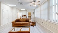 Located at 1912 11th St in Wichita Falls, TX, this efficiently designed single-floor unit offers a thoughtfully arranged layout that maximizes functionality within a cozy footprint. The open-concept living and sleeping area is brightened by a large bank of windows dressed with vertical blinds, allowing generous natural light to fill the space. Light-toned luxury vinyl plank flooring runs throughout, complementing the neutral wall palette and contributing to an airy, cohesive feel. A ceiling fan with integrated lighting anchors the living area, which accommodates both a seating arrangement and a sleeping area with a dedicated closet nearby for storage. The kitchen is a standout feature, outfitted with crisp white cabinetry, dark granite countertops, a classic subway tile backsplash, and a full suite of stainless steel appliances including a refrigerator, range, dishwasher, and microwave. A skylight above the kitchen adds an additional source of natural light. The bathroom is finished with a granite-topped vanity with white cabinetry, tile flooring, and a shower-tub combination. A drop ceiling with recessed lighting and ventilation is consistent throughout the unit, lending a clean, uniform look to the overall interior.
