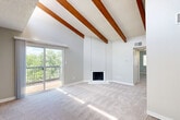 Located at 10700 E Dartmouth Ave in Denver, CO, this 2-bedroom, 2-bathroom residence offers a well-designed single-floor layout that maximizes comfort and functionality. The living room is the architectural centerpiece of the home, showcasing soaring vaulted ceilings adorned with rich, exposed wood beams and a textured ceiling finish. A corner fireplace adds warmth and character, while sliding glass doors open onto a private balcony with green tree-line views, flooding the space with natural light. Soft carpeting and neutral tones throughout create a clean, inviting atmosphere. The galley-style kitchen is thoughtfully appointed with white shaker cabinetry, speckled quartz countertops, a stainless steel sink, and wood-look vinyl plank flooring, providing ample storage and prep space. Both bedrooms are comfortably sized, featuring plush carpeting, textured ceilings, and windows with views of the surrounding greenery. The two full bathrooms are finished consistently with wood-look flooring, white tile tub-shower surrounds, updated fixtures, and quartz-topped vanities. A dedicated closet and ceiling fan complete the practical features of this well-appointed Denver residence.