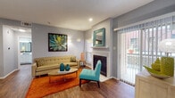 This single-floor residence combines functional design with vibrant style across its well-organized layout. The living room serves as the centerpiece of the home, featuring warm hardwood-style flooring, a classic fireplace with a white mantel, and a sliding glass door that opens to an outdoor balcony, allowing natural light to fill the space. The gray walls provide a neutral backdrop that complements the room's colorful accents.

The living area flows naturally into a dedicated dining space, which accommodates a round glass-top table and seating, kept intimate yet open. The galley-style kitchen is outfitted with white cabinetry, stone-look countertops, and stainless steel appliances including a refrigerator, range, and dishwasher. A pass-through laundry area with washer and dryer hookups is conveniently accessible directly from the kitchen.

The bedroom offers a carpeted, quiet retreat with generous natural light from windows dressed in patterned drapes and blinds, complemented by a ceiling fan. The bathroom features hardwood-style flooring, white cabinetry with stone countertops, a tub-shower combination, and mirrored closet doors that enhance the sense of space. Textured ceilings and recessed lighting appear throughout, adding to the cohesive, well-finished character of the home.
