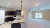 Located in Spring, TX, this single-floor residence offers a well-designed open-concept layout that seamlessly connects the kitchen and living areas. The kitchen is a standout feature, equipped with rich dark espresso cabinetry, a tile backsplash, light countertops, black appliances including a range and built-in microwave, and a peninsula with a stainless steel sink. Pendant lighting and track lighting add functional style throughout the kitchen. Tile flooring anchors the kitchen area, while plush neutral carpet extends throughout the living spaces and bedrooms. Crown molding is present throughout, adding a refined architectural detail to each room. The living room is generously proportioned and benefits from natural light, with double doors leading to an outdoor balcony. Ceiling fans are installed in the living room and bedrooms, enhancing comfort. The bedrooms are well-sized, each featuring closets and windows that allow natural light in. The bathroom includes a combined tub and shower with tile surround, dark vanity cabinetry, and light countertops. Staircase details with white balusters add a classic touch. Overall, the space presents a clean, neutral palette throughout.