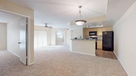 This single-story residence offers a well-designed open-concept floor plan that connects the living area and kitchen seamlessly. The expansive living space is finished with plush neutral carpet and features a textured ceiling with a stylish pendant light fixture, creating a welcoming atmosphere. Ceiling fans are installed throughout, providing comfort and airflow across multiple rooms.

The kitchen is a functional highlight of the space, featuring light wood cabinetry, granite-look countertops, a white subway tile backsplash, and a full suite of black appliances including an electric range, over-the-range microwave, dishwasher, and refrigerator. Track lighting and a tray ceiling detail add character, while wood-look flooring grounds the space. A peninsula with counter seating connects the kitchen to the living and dining areas.

The bedrooms are generously sized, each with soft carpet, ceiling fans, natural light from windows, and ample closet space with bifold doors. One bedroom includes an en-suite bathroom with dual vanities, a large mirror, and bright overhead lighting. The bathrooms are finished with wood-look flooring, light wood vanities, and tub-shower combinations, offering a clean, functional aesthetic throughout.