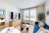 This thoughtfully designed one-bedroom, one-bathroom residence in Houston, TX offers a cohesive open-concept layout with modern finishes throughout. Light wood-look flooring flows seamlessly across the entire space, lending a clean, contemporary aesthetic. The living room is bright and inviting, featuring large windows that allow ample natural light to fill the room, creating an airy atmosphere. The kitchen is a standout, equipped with stainless steel appliances including a range, microwave, and refrigerator, complemented by crisp white shaker cabinetry extending to the ceiling, a textured tile backsplash, granite countertops, and a peninsula with bar seating — ideal for casual dining or entertaining. The bedroom offers a comfortable, well-proportioned retreat highlighted by soothing blue accent walls, a ceiling fan, and large windows with outdoor views. A closet provides dedicated storage, while the bathroom features a granite-topped white vanity with ample cabinetry, a walk-in shower with tile surround, and direct access to the bedroom. A hallway connects the rooms efficiently, completing this well-organized single-floor layout designed for functional and comfortable everyday living.