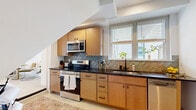 Located at 223-225 Henry St in Petersburg, VA, this efficiently designed single-floor unit offers a well-planned layout that maximizes every square foot. The living room is a bright, welcoming space featuring light hardwood-style flooring, recessed lighting, a wall-mounted split HVAC unit, and windows with blinds that allow natural light to fill the room. The kitchen is a functional standout, outfitted with warm wood cabinetry, dark countertops, and a distinctive herringbone-patterned tile backsplash. Stainless steel appliances — including a range, microwave, and dishwasher — provide a complete cooking setup, while a window above the sink adds natural light. The bedroom is a calm, serene retreat with neutral walls, a wall-mounted split unit, and ample room for a full-sized bed and furnishings. The bathroom features a clean, modern aesthetic with a wood-toned vanity, white countertop, matte black fixtures, and a large mirror. A dedicated laundry area and two closets add practical storage throughout. Light flooring runs consistently across the unit, contributing to a cohesive and airy feel. The overall design balances contemporary finishes with functional efficiency.