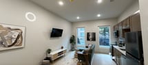 Located at 1818 Fifth Ave in Troy, NY, this 380-square-foot single-floor studio apartment offers a thoughtfully designed open-concept layout that maximizes every square foot. The living and kitchen areas flow seamlessly together, creating an efficient and functional living space. The kitchen is outfitted with a full suite of stainless steel appliances, including a range with oven, over-the-range microwave, dishwasher, and refrigerator. Warm-toned, shaker-style cabinetry extends to the ceiling for ample storage, complemented by a white tile backsplash and light countertops. Light wood-tone flooring runs throughout the main living area, lending warmth and continuity. The living space is brightened by windows that allow natural light to filter in, offering views of the surrounding streetscape. Recessed lighting provides additional illumination throughout. The bathroom features a wood-framed vanity mirror, single-sink vanity with wood cabinetry, and patterned tile flooring, maintaining the same modern aesthetic found throughout the unit. The floorplan also reveals an entry corridor and a walk-in shower area, making the most of the available space. Overall, this studio presents a clean, contemporary aesthetic well-suited for urban living in Troy, NY.